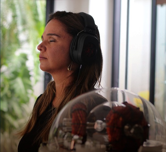 Mulher com fones RASHA® em repouso, com o equipamento em primeiro plano